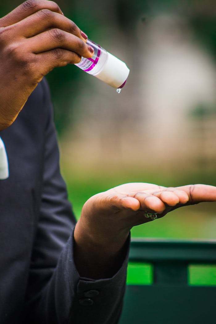 Close-up of hands using hand sanitizer outdoors, promoting hygiene.